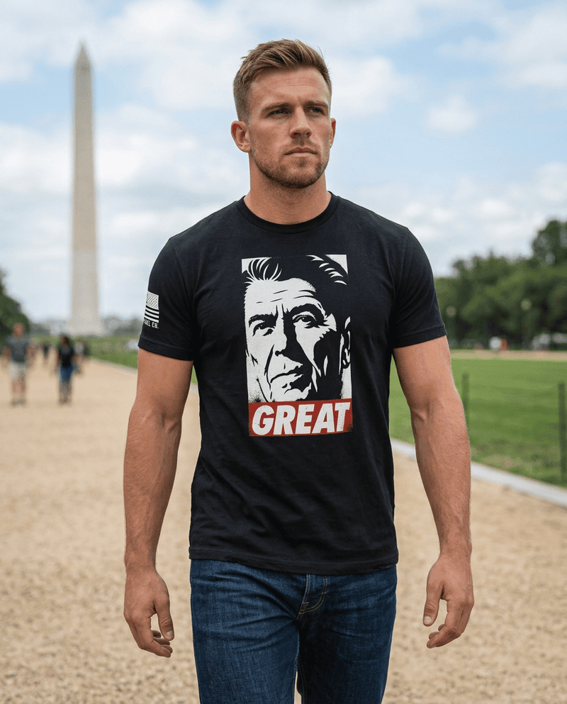 Man walking near the Washington Monument wearing a black T-shirt with a Ronald Reagan "GREAT" graphic.