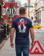 Man on NYC street in navy 3 Truck 9/11 25th anniversary "We're Still Heading Up" t-shirt, unique lifestyle design.