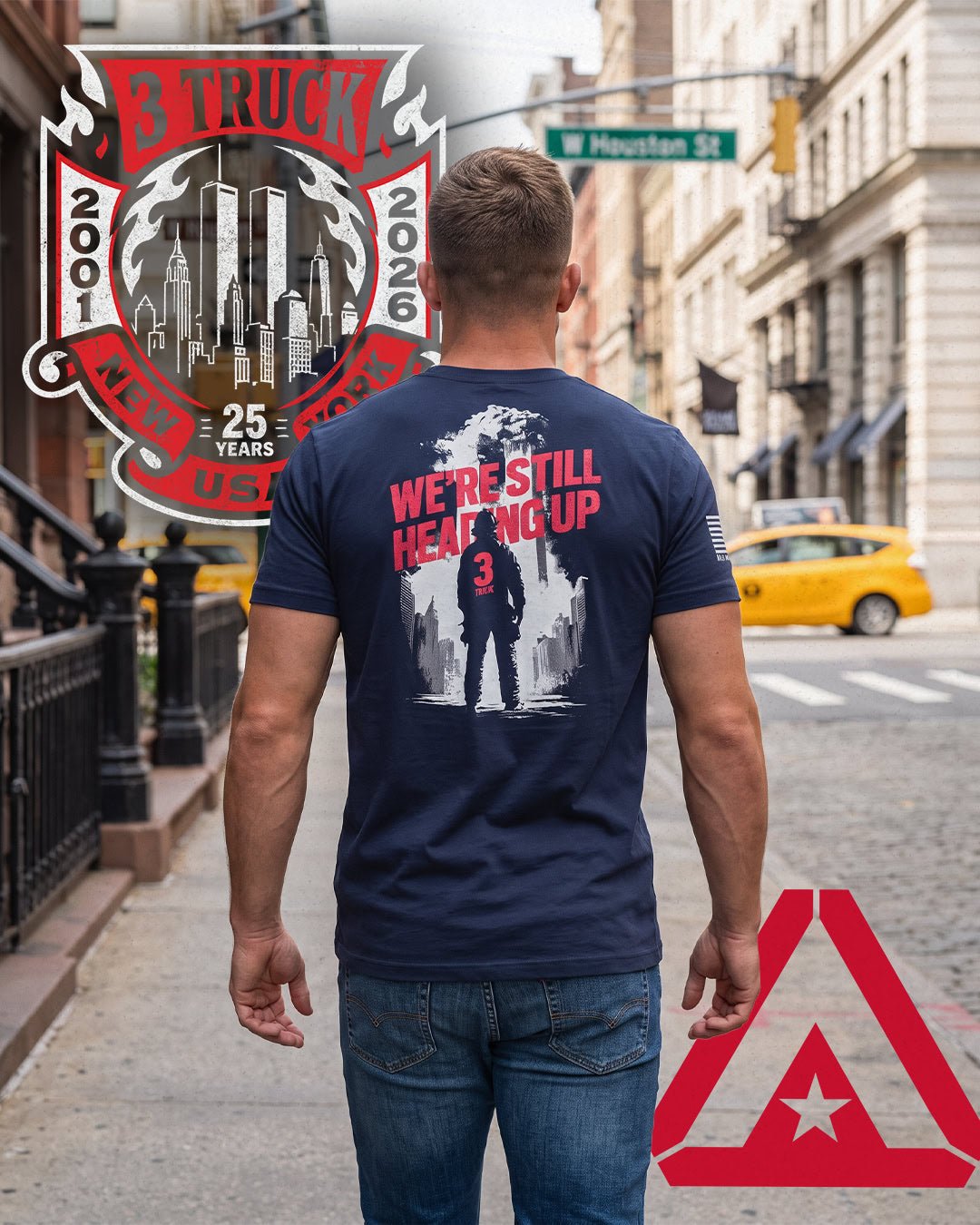 Man on NYC street in navy 3 Truck 9/11 25th anniversary "We're Still Heading Up" t-shirt, unique lifestyle design.