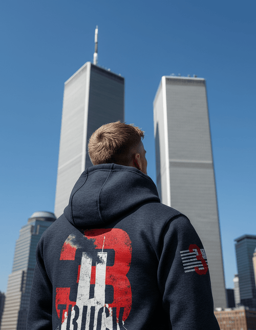 Man facing Twin Towers in navy hoodie back with 9/11 "3 TRUCK" graphic and American flag sleeve.