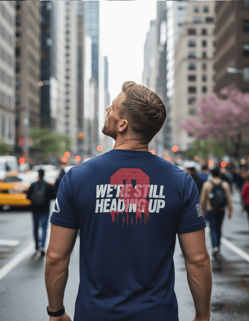 Man in a busy city street wearing a navy blue t-shirt with a back graphic and a DIA logo on the sleeve.