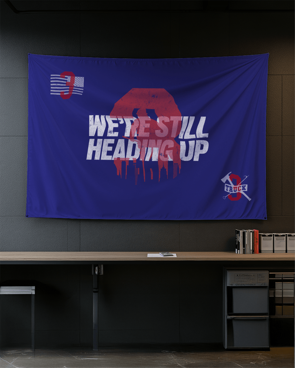 Modern office blue Truck 3 memorial flag with a red number 3, skyline, and firefighting tools on a dark wall.