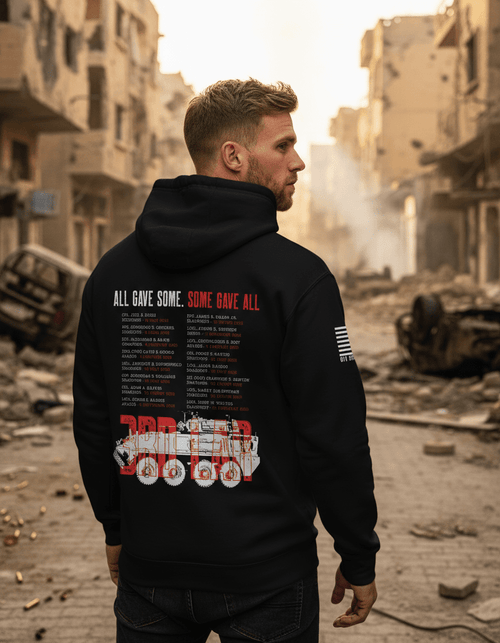 Man in a devastated urban setting wearing a black 3rd LAR memorial hoodie with a red graphic and white American flag sleeve.