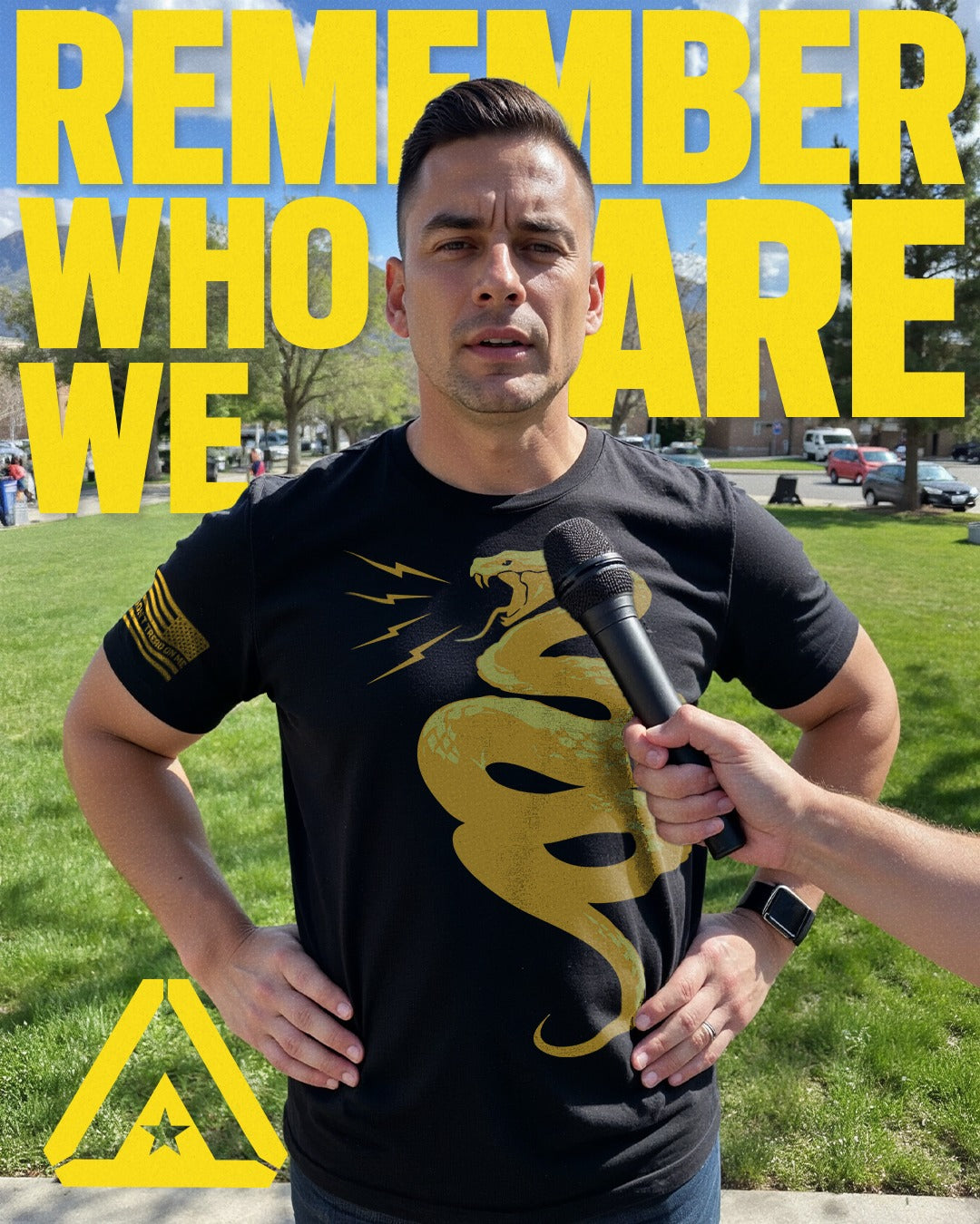 Man wearing a black t-shirt with a yellow logo, holding a microphone, with text 'REMEMBER WHO WE ARE' in the background.
