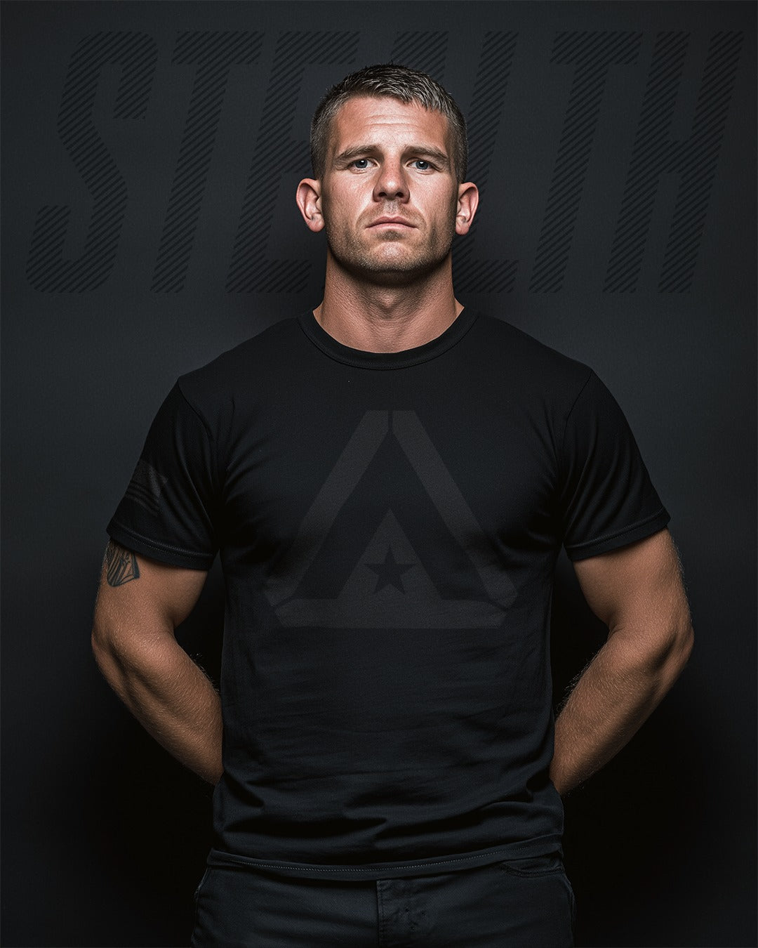 Man wearing a black t-shirt with a logo on a dark background