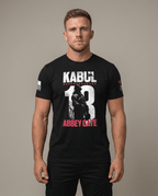 Man in studio wearing black t-shirt featuring Kabul 13 Abbey Gate graphic and American flag sleeve patch.