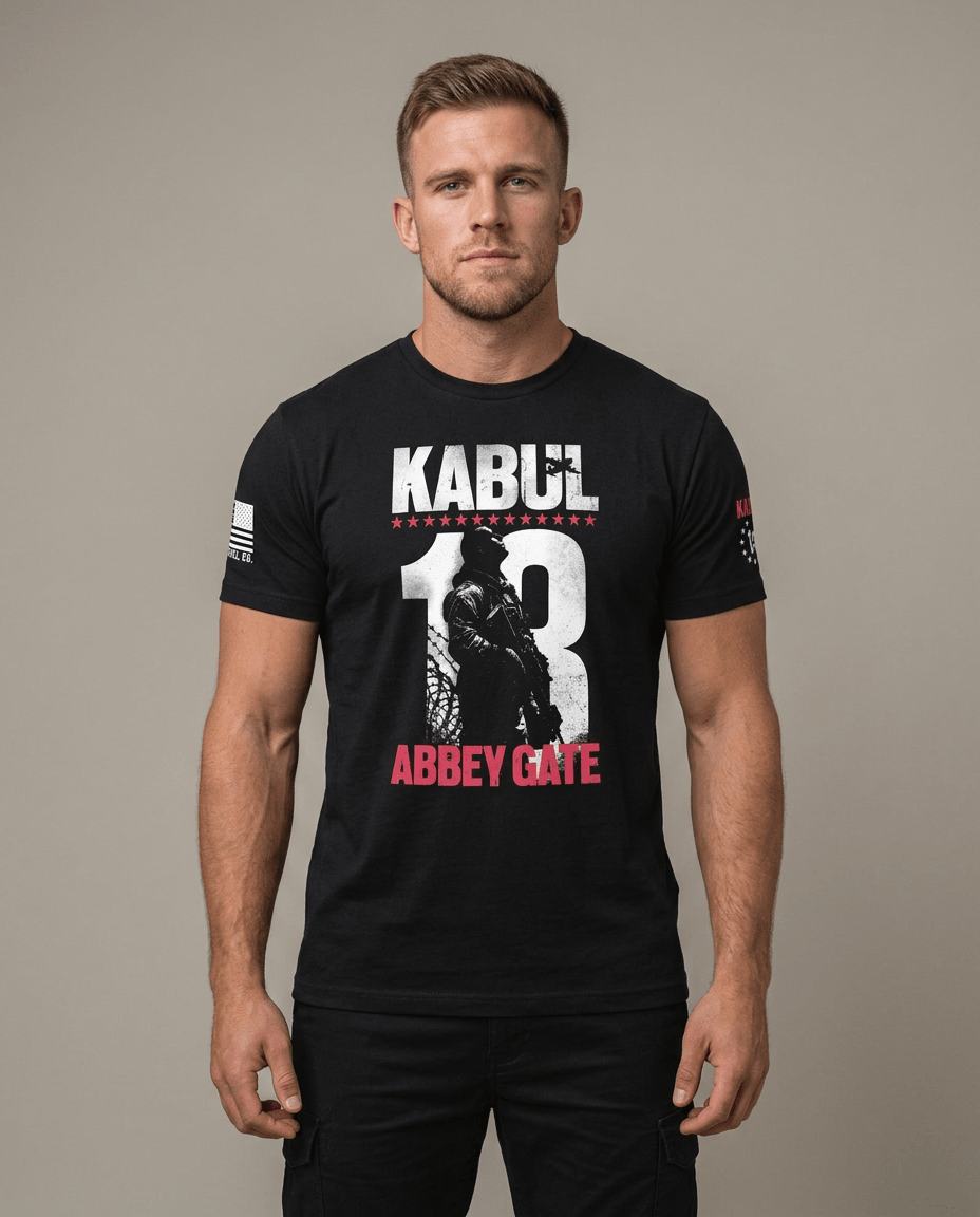 Man in studio wearing black t-shirt featuring Kabul 13 Abbey Gate graphic and American flag sleeve patch.