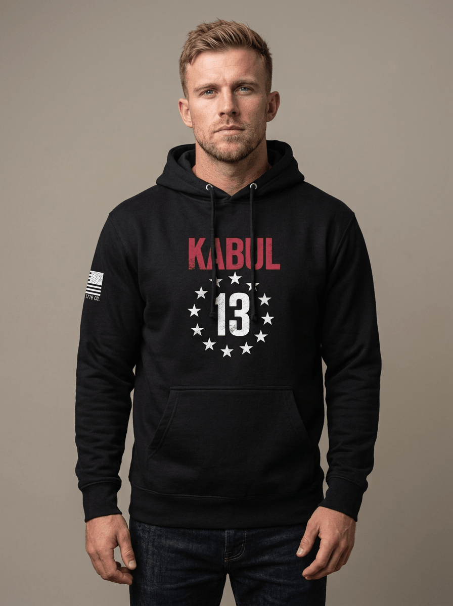 Man in studio wearing black hoodie with red "KABUL" and star-circled 13 chest emblem, with American flag sleeve patch.