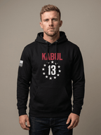 Man in studio wearing black hoodie with red "KABUL" and star-circled 13 chest emblem, with American flag sleeve patch.