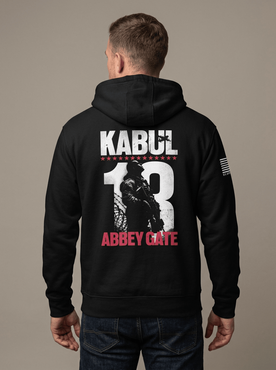 Man from behind in studio wearing black hoodie with Kabul 13 Abbey Gate back graphic and American flag sleeve patch.