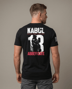 Man from behind in studio wearing black t-shirt featuring Kabul 13 Abbey Gate back graphic and American flag sleeve patch.