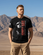 Man in black Abbey Gate "Remember Their Names" t-shirt, soldier graphic, desert background, and American flag on sleeve.
