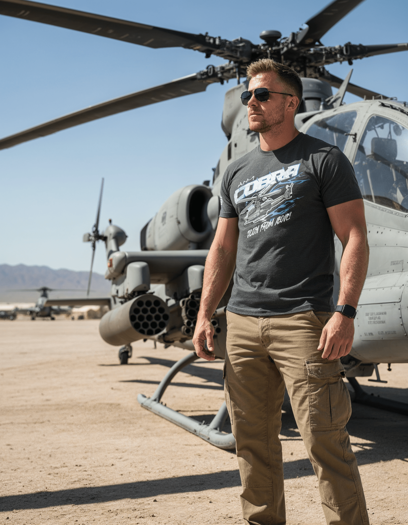 Man by an AH-1 Cobra helicopter wearing a charcoal gray AH-1 Cobra t-shirt with "Death From Above!" text.