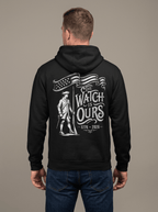 Man from behind in studio wearing black hoodie with "THE WATCH IS OURS 1776-2026" minuteman back graphic.