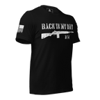 Three-quarter view of a black t-shirt with a distressed rifle graphic, "BACK IN MY DAY M-14" text, and American flag on the sleeve.