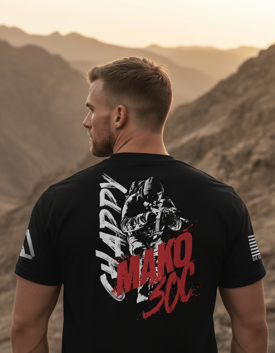 Man in desert mountains wearing black "CHAPPY MAKO 30C" t-shirt with soldier graphic and flag on sleeve.