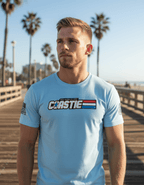 A man stands on a sunny boardwalk with palm trees wearing a light blue "COASTIE" t-shirt and American flag.