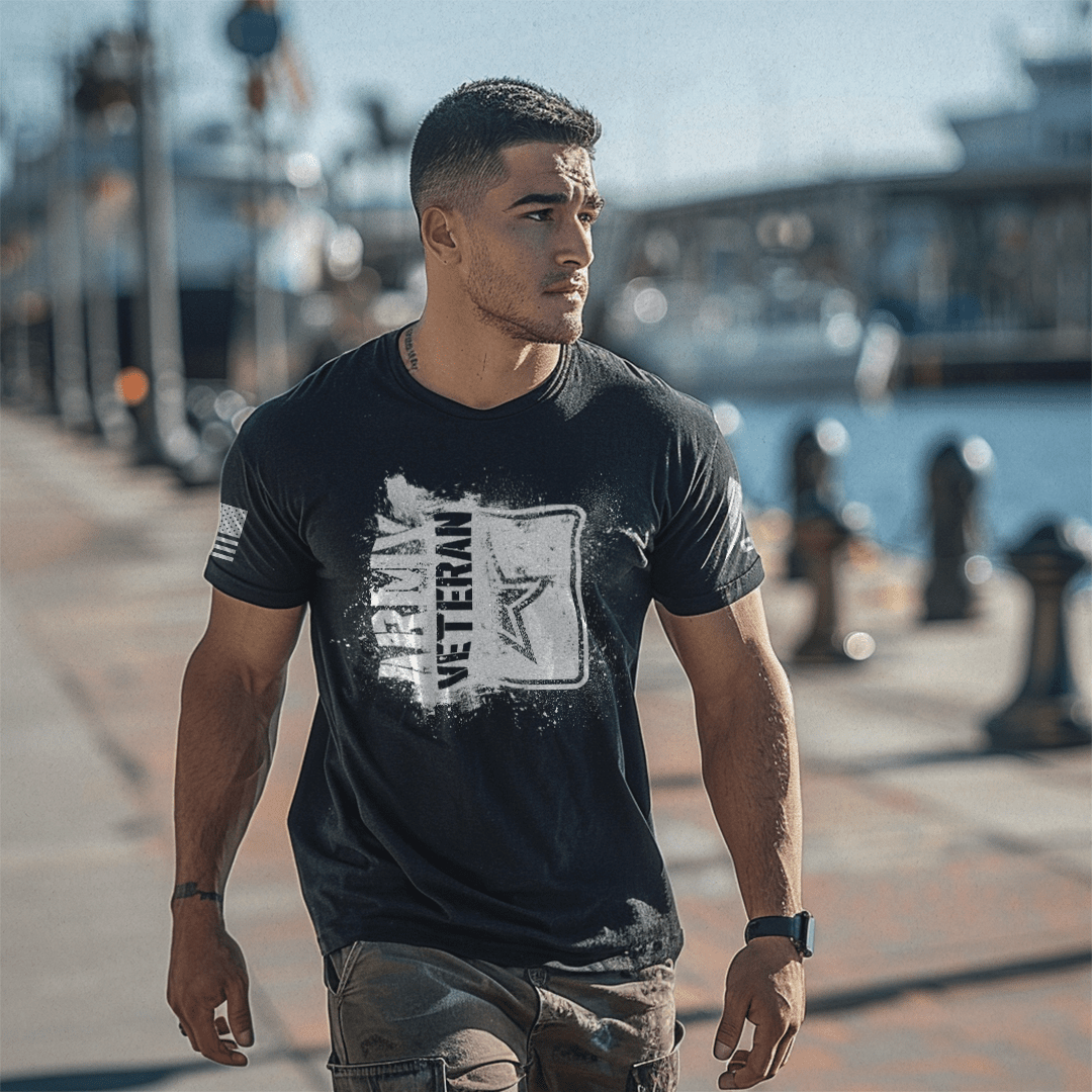 A man walks along a sunny harbor wearing a black "ARMY VETERAN" t-shirt with an American flag and a DIA logo on the sleeves.
