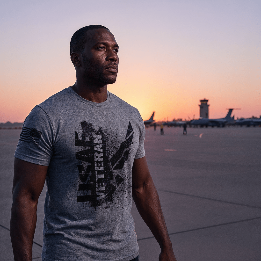 A man stands on an airfield at sunset, wearing a gray "USAF VETERAN" t-shirt with an American flag on the sleeve.