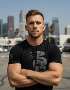 Man in city with black t-shirt front featuring grey tonal snake and grey American flag on sleeve.