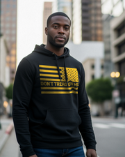 Man wearing DIA Don't Tread On Me Hoodie featuring a gold American flag design, standing in an urban setting