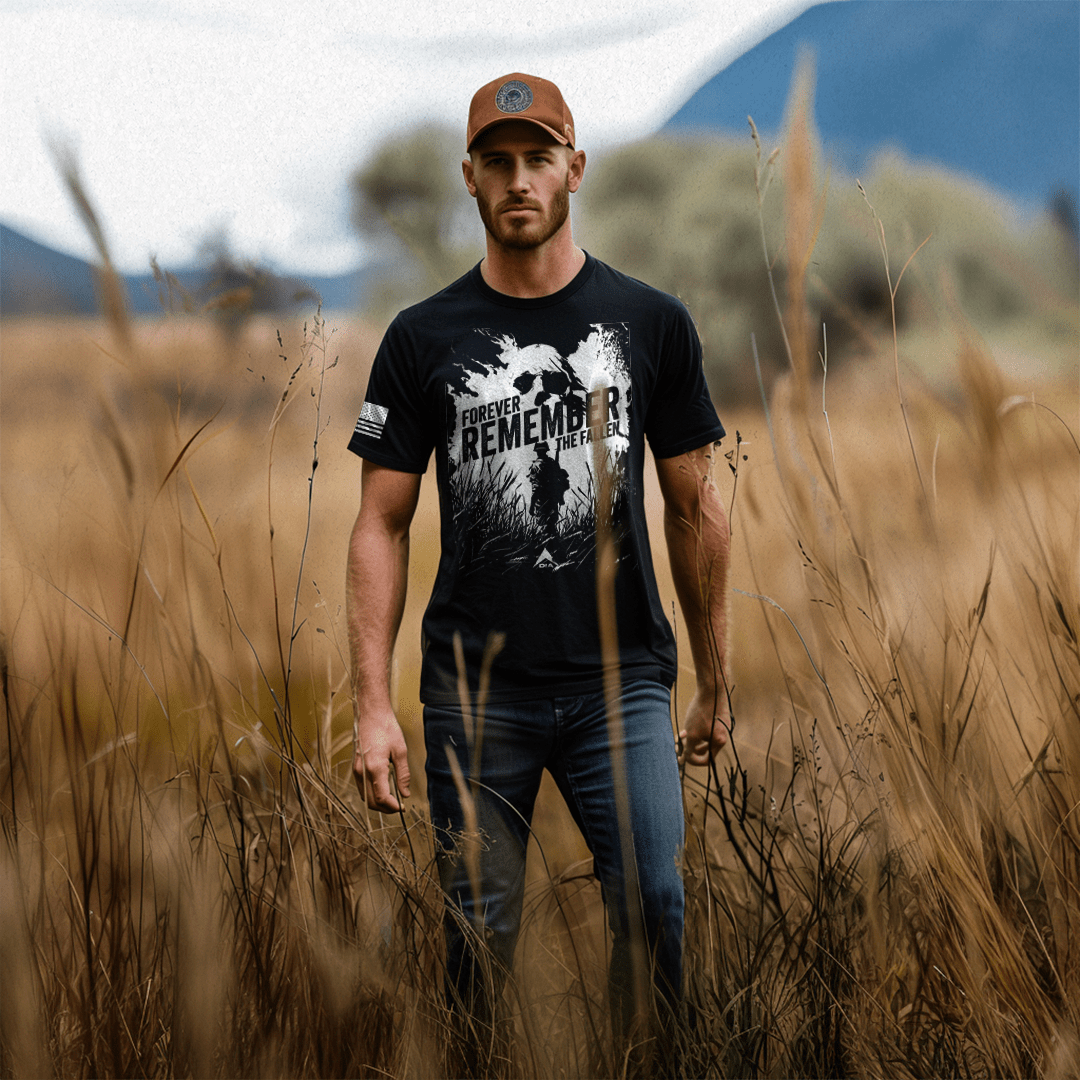 Man in a golden field wearing a black "Forever Remember the Fallen" shirt, American flag on sleeve.