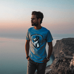 Man overlooking the ocean at sunset, wearing a Aqua blue t-shirt featuring a lion crest and DIA logo.