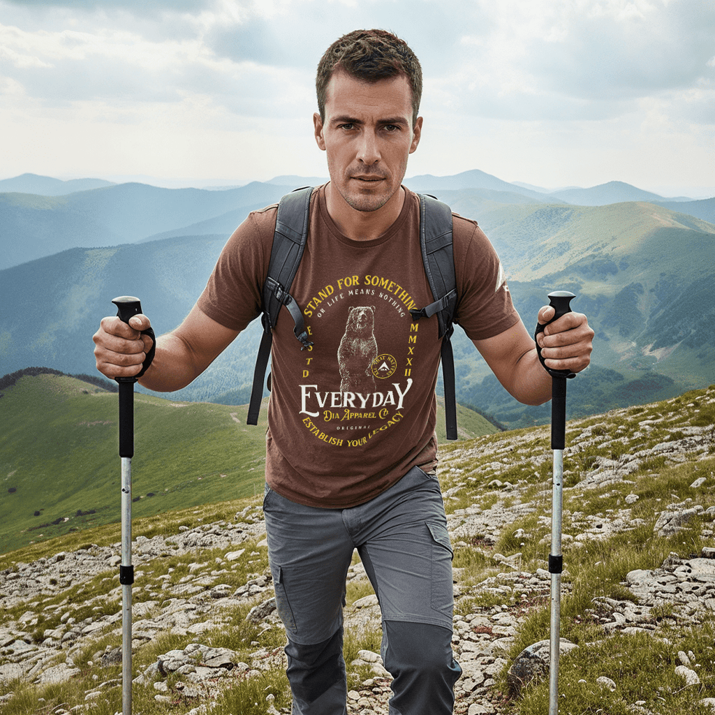 A man hiking in a brown t-shirt featuring a standing bear graphic and "EVERYDAY" text.