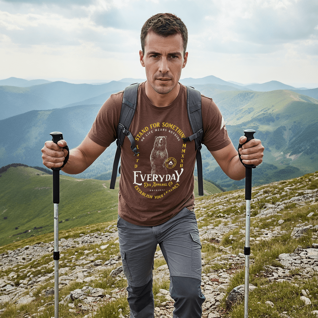 A man hiking in a brown t-shirt featuring a standing bear graphic and "EVERYDAY" text.