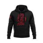Black hoodie featuring red "STAY FERAL" snarling raccoon graphic and an American flag patch on the right sleeve.