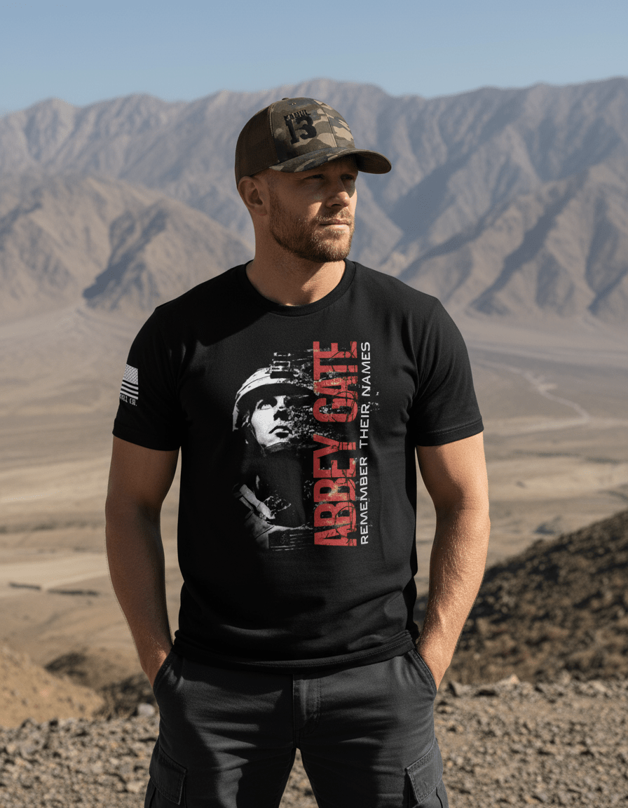 Man in desert mountains wearing a camo Kabul 13 hat and a black Abbey Gate DIA t-shirt.