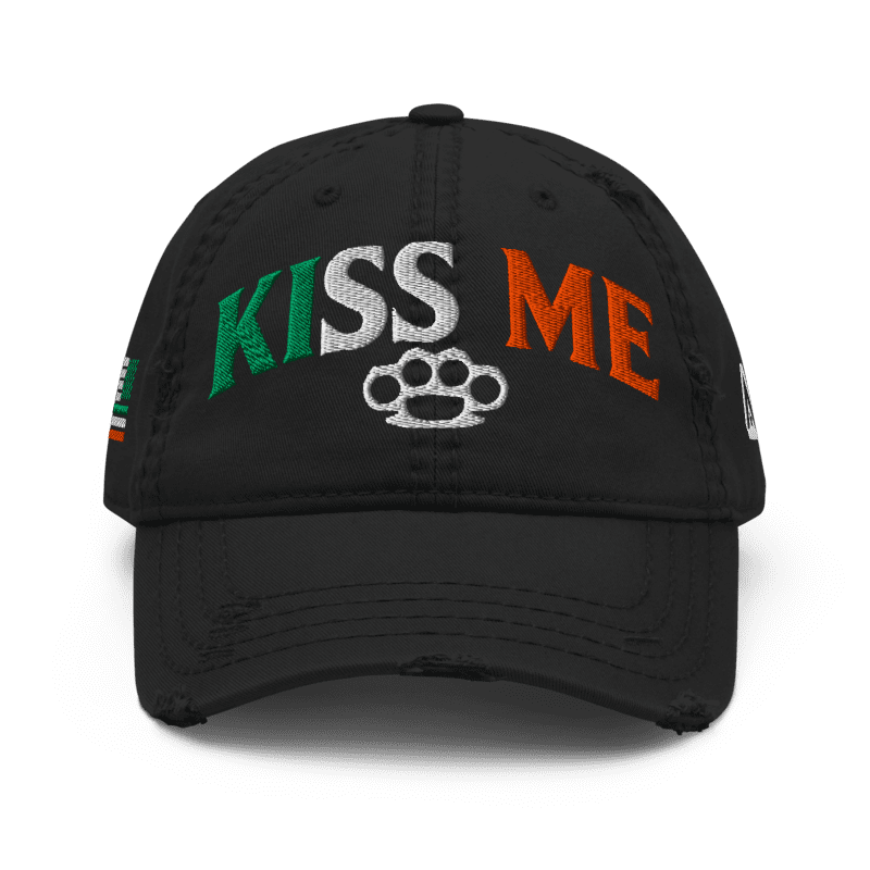 Black distressed ball cap, front view, with "KISS ME" in Irish flag colors and an Irish flag graphic on the side.