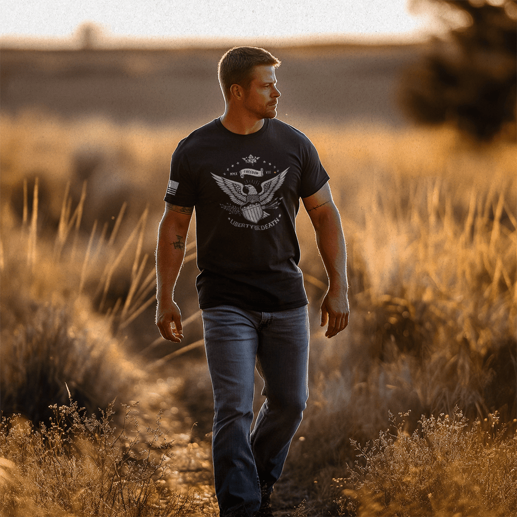 A man walks through a sunlit field wearing a black Liberty or Death t-shirt with a white DIA logo.