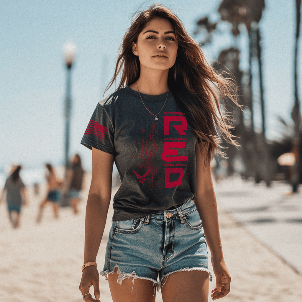 Woman at a beach wearing denim shorts and a charcoal RED Air Force edition DIA shirt.