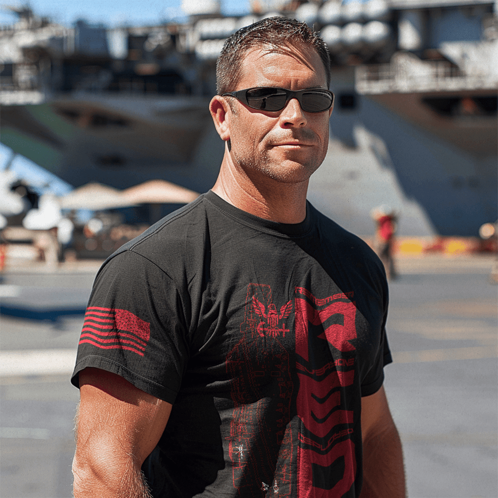 Man in sunglasses on a flight deck wearing a black RED navy edition DIA t-shirt with red graphics.