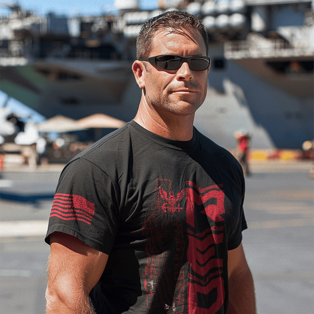Man in sunglasses on a flight deck wearing a black RED navy edition DIA t-shirt with red graphics.