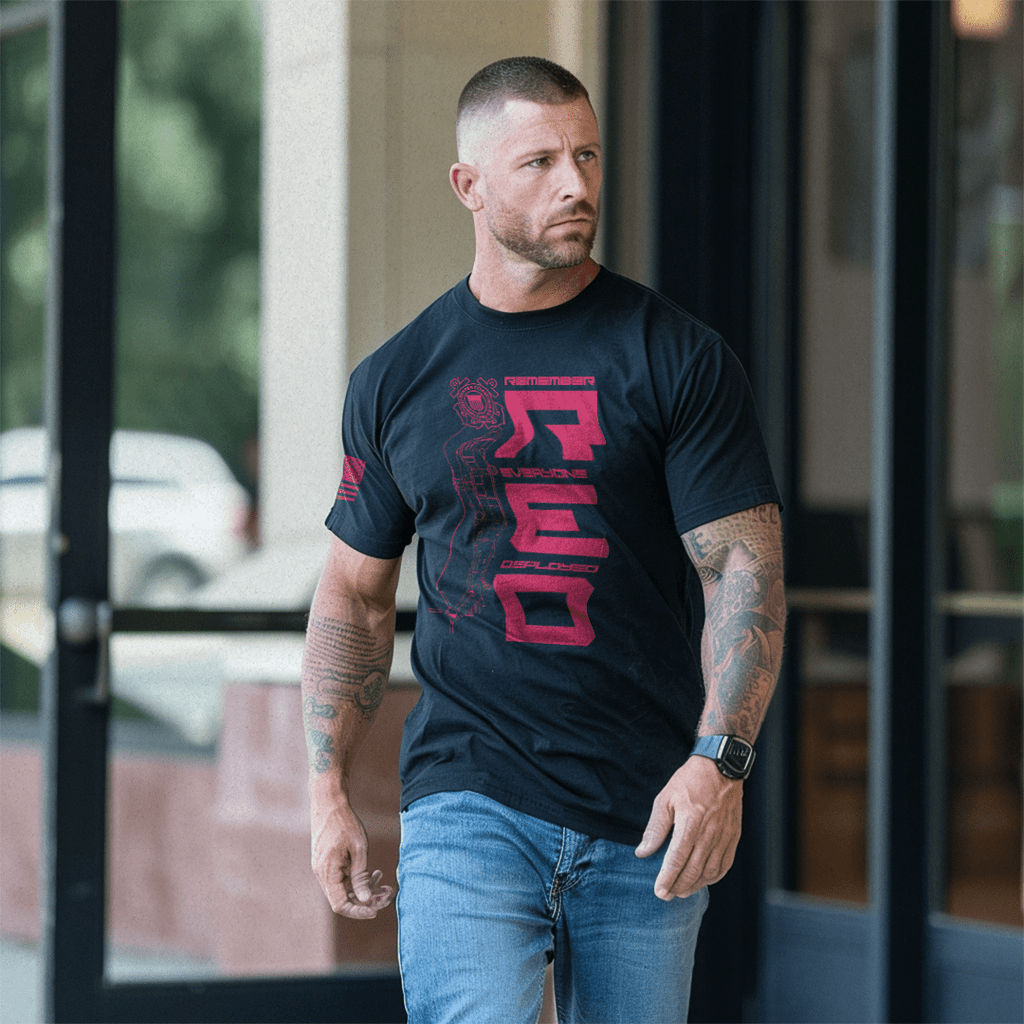Man walking outside a glass door wearing a black USCG edition RED DIA shirt and blue jeans.