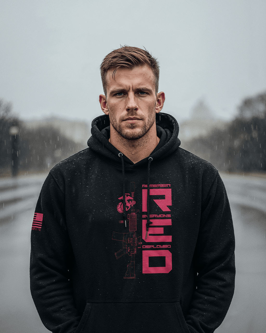 Man outdoors in the rain, wearing a black hoodie with a "RED" graphic, USMC emblem, and red American flag on the sleeve.