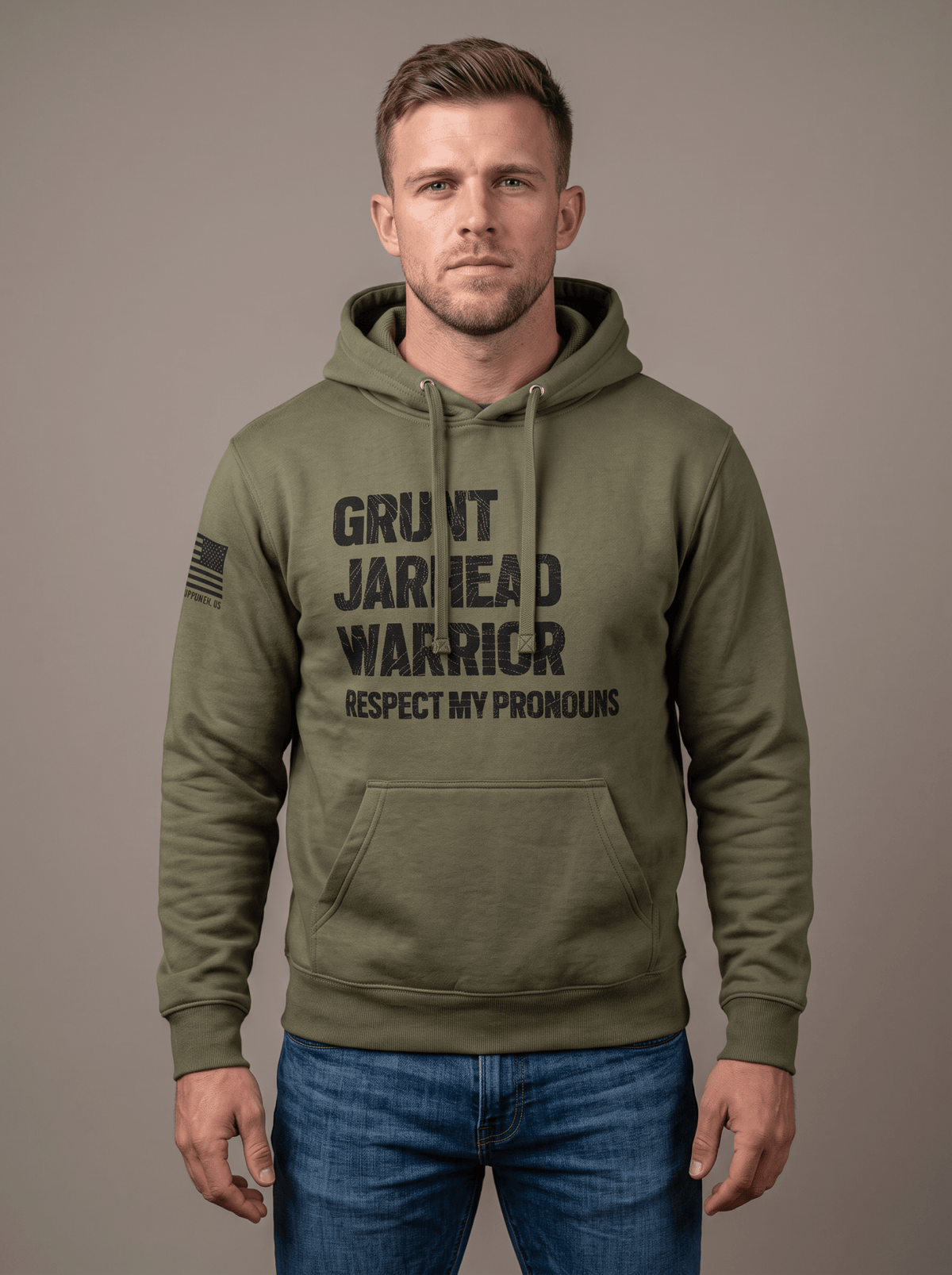Man standing in studio facing forward, wearing olive green hoodie with "GRUNT JARHEAD WARRIOR RESPECT MY PRONOUNS" graphic.   
