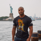 Muscular man by water wearing a black Unshackle Liberty t-shirt with flaming statue and white sleeve flags.