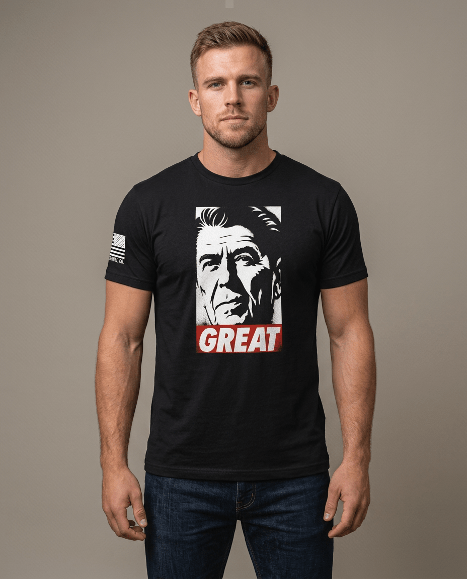 Man in studio wearing black t-shirt featuring Ronald Reagan portrait graphic with red "GREAT" text block.