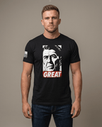 Man in studio wearing black t-shirt featuring Ronald Reagan portrait graphic with red "GREAT" text block.