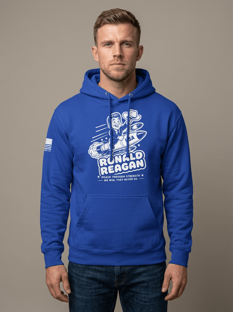 Man in studio wearing a royal blue hoodie with a cartoon Ronald Reagan missile graphic and an American flag sleeve patch.