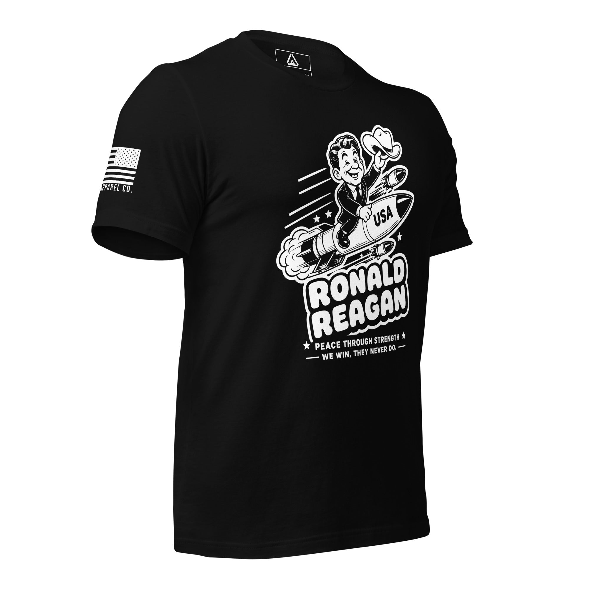 Black t-shirt angled right, featuring a cartoon Ronald Reagan on a missile graphic and American flag sleeve patch.