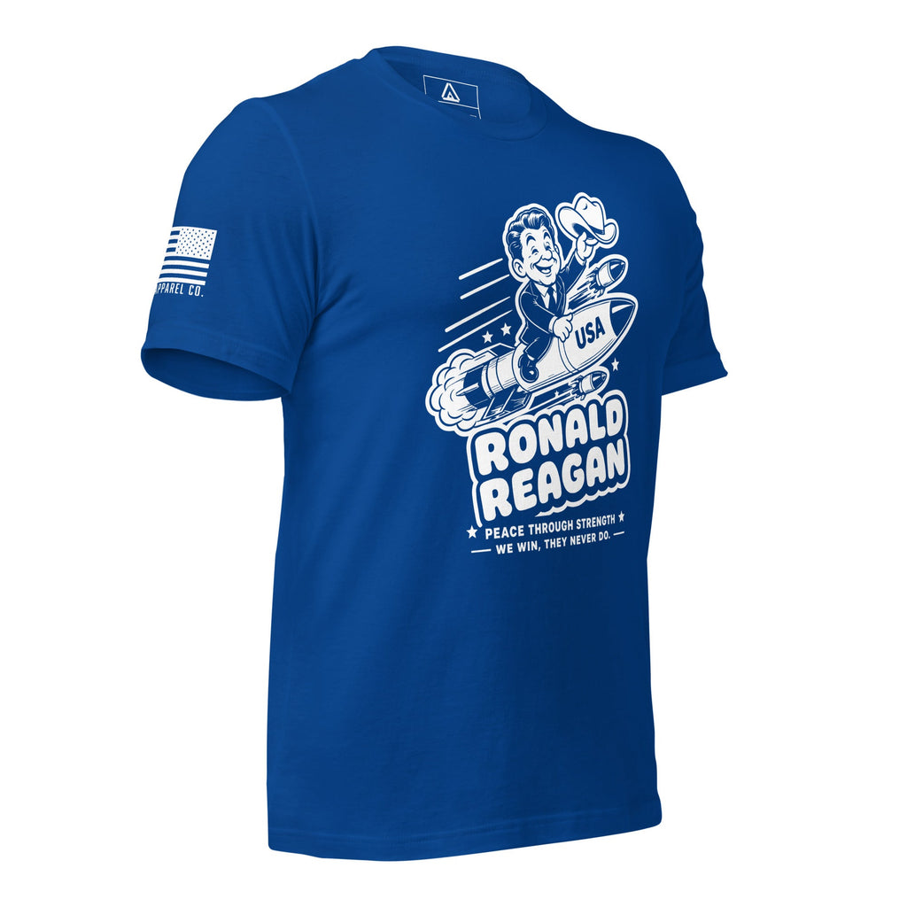 Blue t-shirt angled right, featuring a cartoon Ronald Reagan on a missile graphic and American flag sleeve patch.