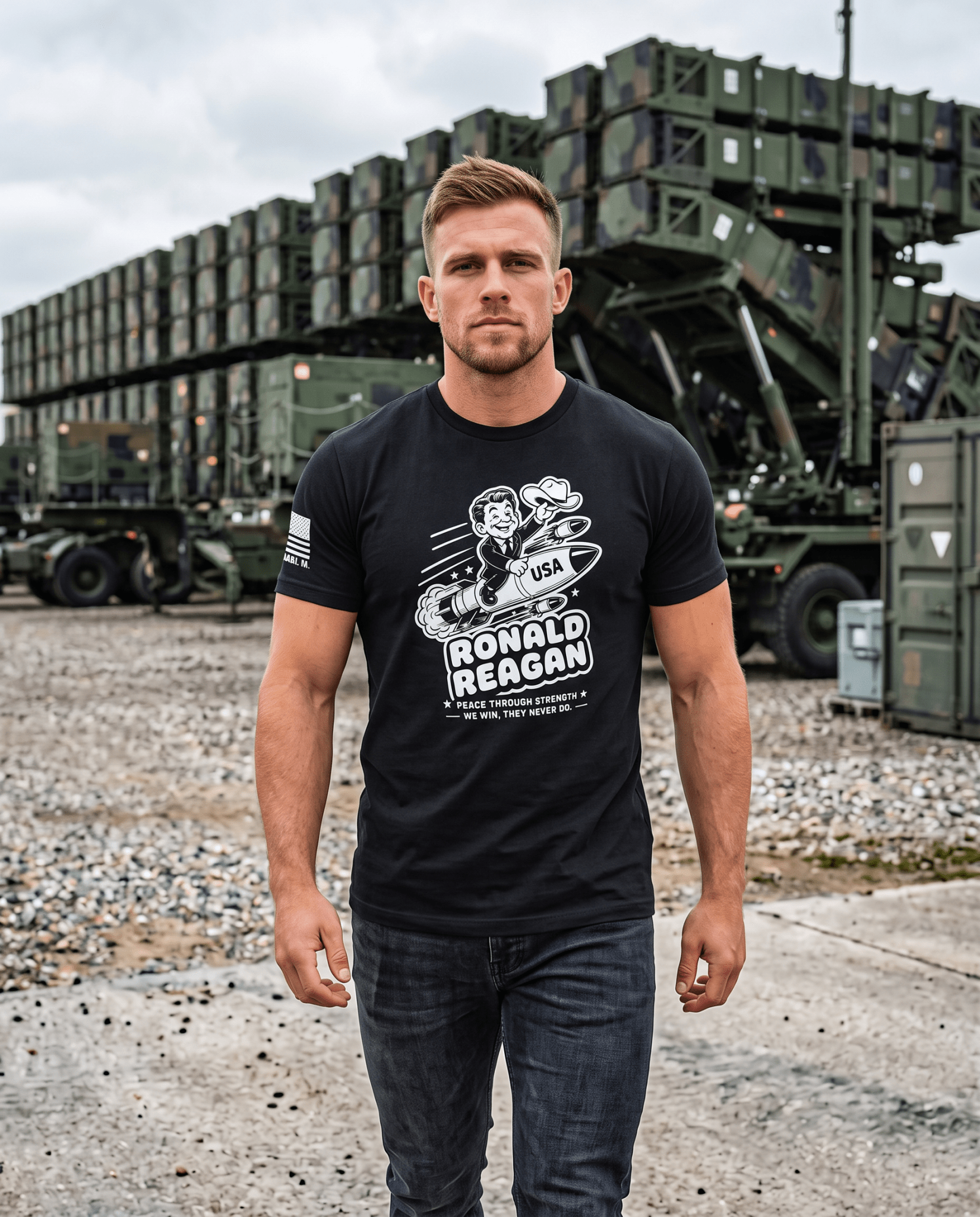Man at military site wearing black t-shirt with cartoon Ronald Reagan on a missile graphic and "Peace Through Strength".