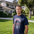 Man in a suburban yard wearing a navy Self Governed Self Made t-shirt with a flag-themed tree graphic and DIA logo.
