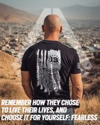 Bald man overlooking a city, black Kabul memorial shirt with a white distressed flag, fallen names, and 13 stars.