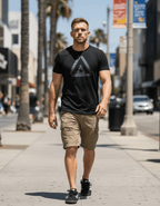 Man walking on city sidewalk wearing black t-shirt front with a large grey DIA logo and grey American flag on sleeve.