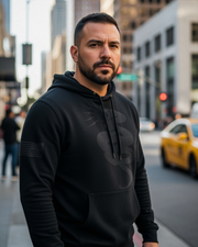 Man wearing DIA Don't Tread On Me Stealth Hoodie featuring a snake design and American flag, standing on an urban street.